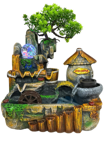 A decorative miniature fantasy waterfall fountain with a small tree, stone arches, a water wheel, a stone mill, a glowing orb, and a thatched-roof structure labeled 'Welcome'