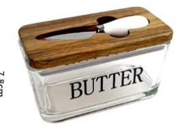 A clear glass butter container with a brown wooden lid and a white interior, labeled 'BUTTER' in black text. A small knife is tucked into the slot in the lid.