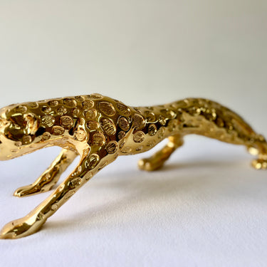 Close side view of the gold prowling big cat sculpture showing the textured gold finish