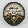 A round vintage-style wall clock with a black frame and a decorative dial featuring Roman numerals, gold-toned gears, antique car and train illustrations, and the text 'OLD TOWN EST. 1883'.